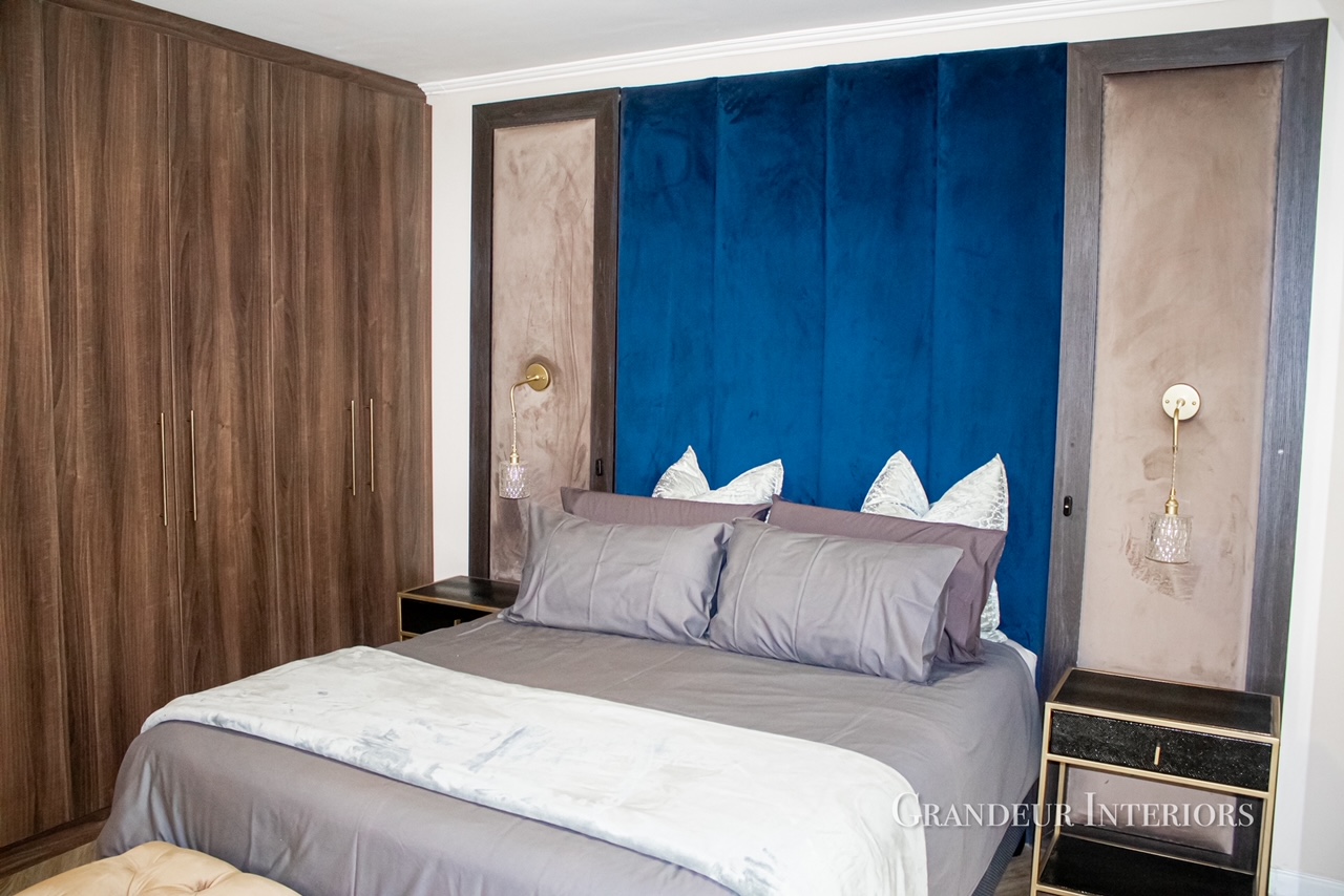 Master bedroom with deep blue velvet headboard and walnut joinery