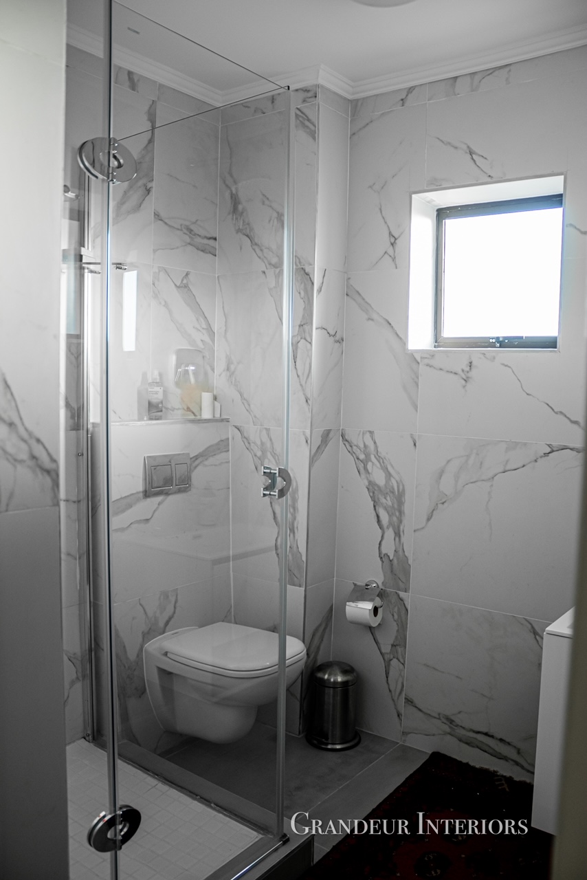 Marble-tiled ensuite shower with frameless glass enclosure