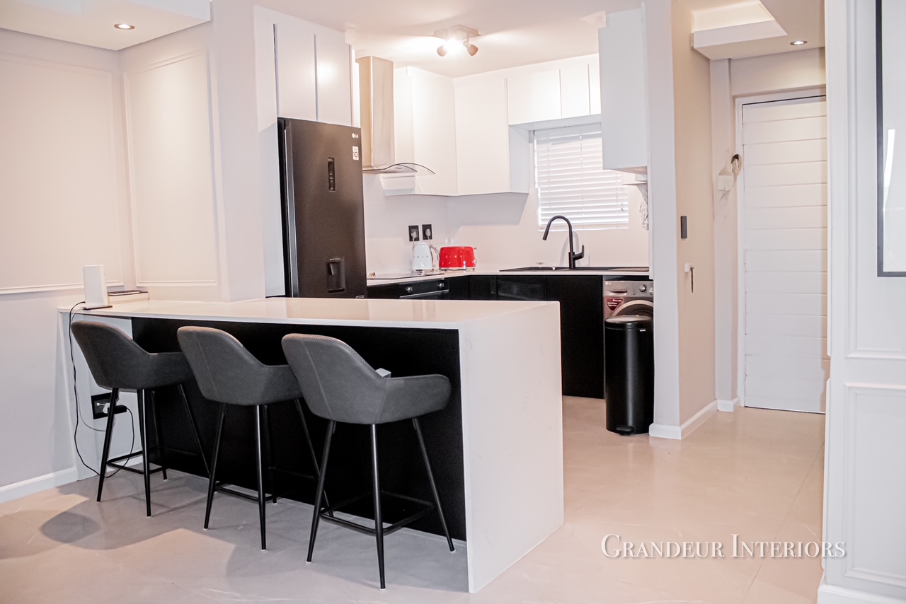 Bespoke white and black kitchen with breakfast bar and upholstered stools