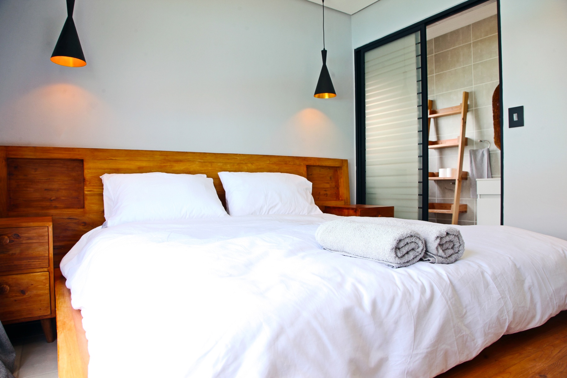 Master bedroom with custom timber headboard and pendant lighting