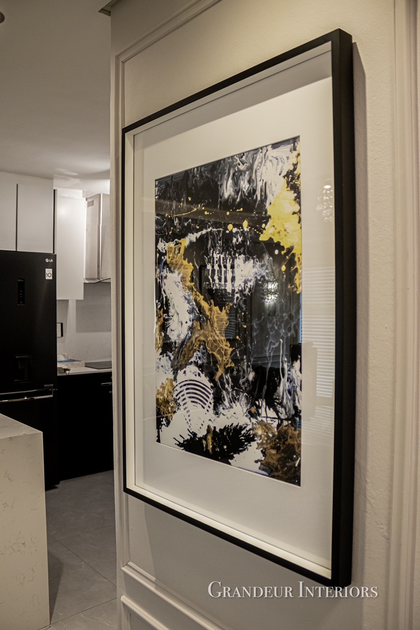 Framed abstract artwork in black, white and gold beside the kitchen