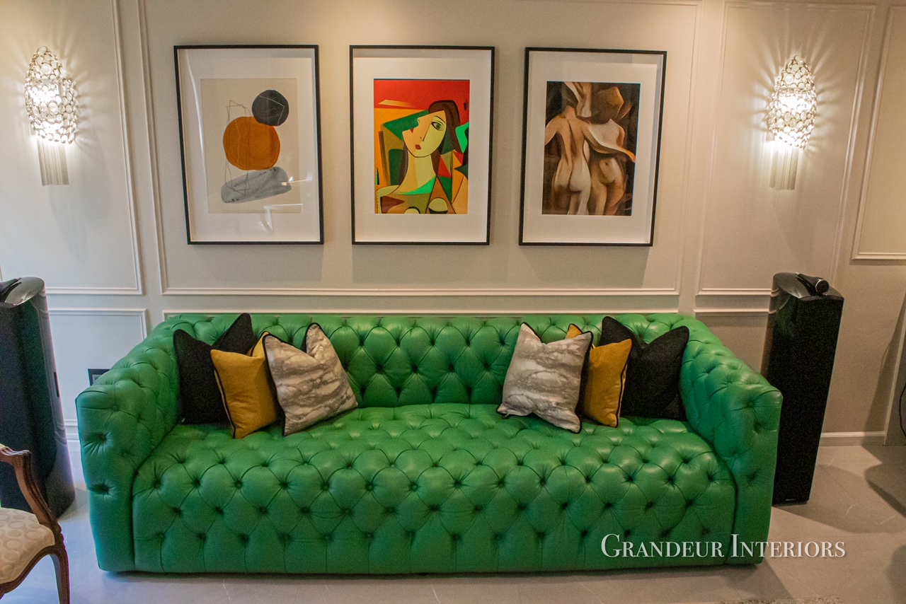 Emerald Chesterfield sofa with layered scatter cushions beneath a triptych of framed art