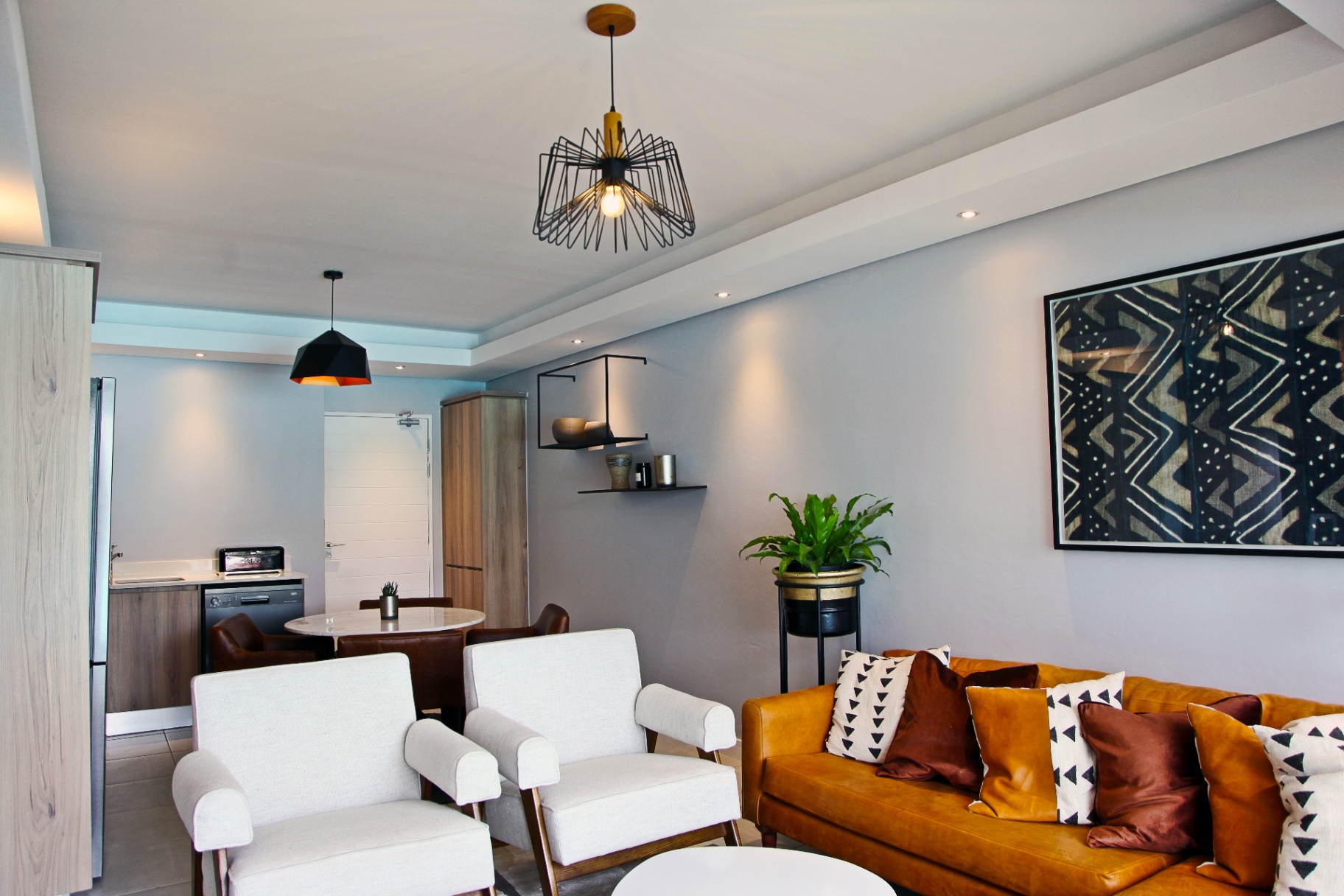Living and dining area with pendant lighting and mudcloth artwork